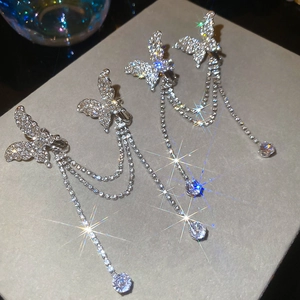 Nahaufnahme silberner Schmetterlings-Ohrklemmen mit glitzernden Strassfransen und Stern-Effekt