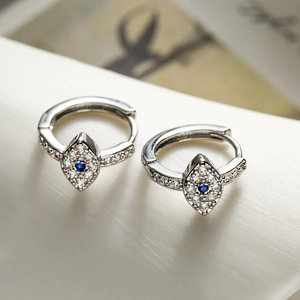 Detail von silbernen Huggie-Ohrringen mit blauem Zirkonia-Auge und Kristallen