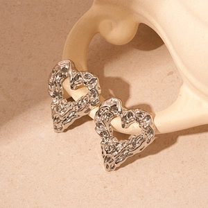 Macro shot of silver molten metal heart earrings with irregular textured surface finish