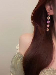 Vue latérale macro de longues boucles d'oreilles fleurs avec cristaux dégradés roses