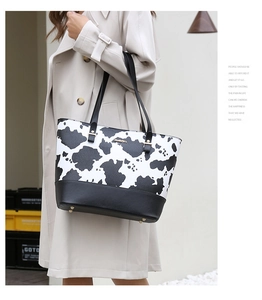 Détail du sac cabas à imprimé vache avec anses en simili cuir noir et clous de fond en métal