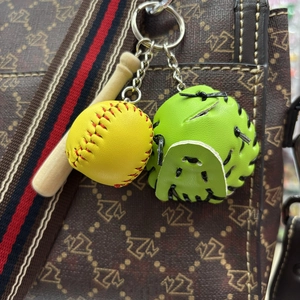 Close-up of mini baseball keychain with wood bat, yellow ball and green glove on bag