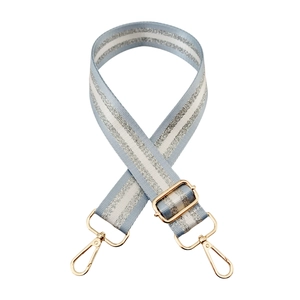 Close-up of woven blue and white adjustable shoulder strap with gold metal buckles
