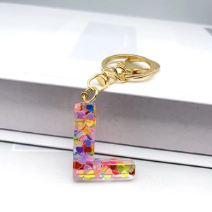 Detailed macro view of letter L keychain with colorful heart sequins and golden metal ring
