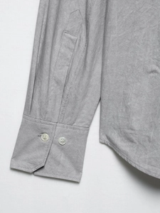 Detail of soft gray cotton shirt showing buttoned cuffs and curved hem stitching