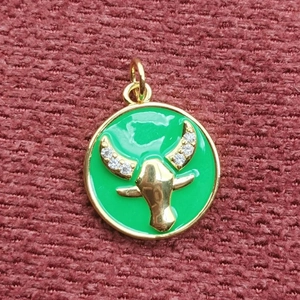 Primo piano del ciondolo totem toro dorato con smalto verde e cristalli lucidi