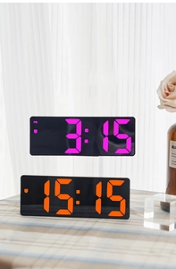 Modern mirror digital alarm clocks showing pink and orange LED time on a desk