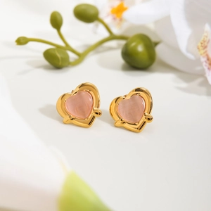 Elegant gold-framed pink cat-eye heart drop earrings displayed on a soft floral background
