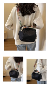 Three-way view of black nylon crossbody bag with colorful patterned strap on model