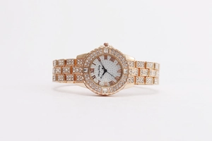 Vue macro détaillée du cadran de montre or rose avec chiffres romains et strass brillants