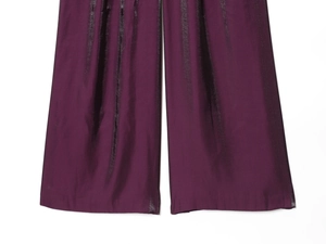 Detailansicht der dunkelvioletten Satin-Stofftextur und des drapierten Saums der Hose