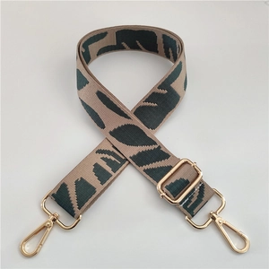 Macro detail of khaki nylon strap with dark green leaf pattern and gold hardware