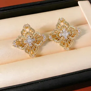 Elegant gold hollow flower earrings with cubic zirconia set in a plush beige jewelry box