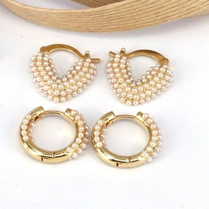 Macro shot of French style gold heart and round hoop earrings with mini white pearls