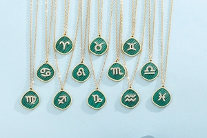 Flat lay of twelve gold necklaces featuring green malachite zodiac pendants with zircons