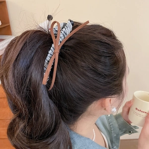 Detail of dog-shaped bow hair clip in black and white plaid fabric on wavy hair