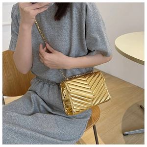 Close-up of golden chevron-quilted crossbody bag with metallic finish and chain strap