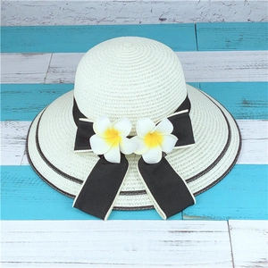 Détail de chapeau de soleil en paille avec ruban noir et fleurs de frangipanier