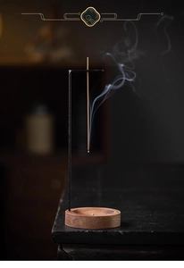 Macro shot of incense burning on a black metal holder with a round wooden base and smoke