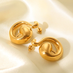 Detailed view of golden irregular abstract earrings on soft beige silk background