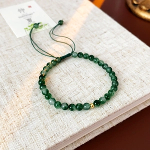 Détail macro d'un bracelet en perles vertes avec breloque dorée et cordon tressé