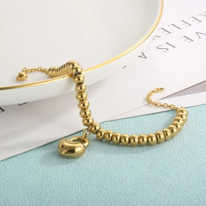 Close-up of golden heart pendant bead chain bracelet with adjustable lobster clasp
