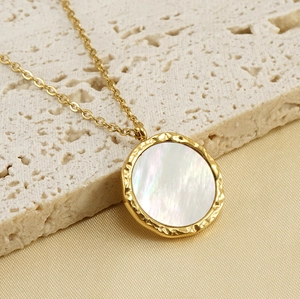 Macro view of 18K gold plated necklace with round shell pendant on natural stone base