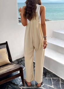 Détail de la combinaison beige à jambes larges et fines bretelles face à l'océan