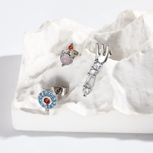Detailed view of silver stud earrings with pink and blue zircons on a white display