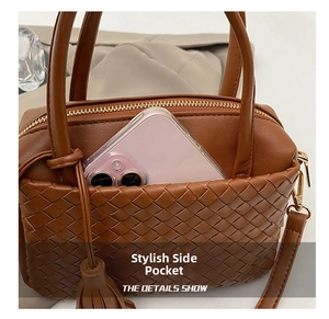 Detailed view of brown woven shoulder bag featuring a side pocket and tassel detail