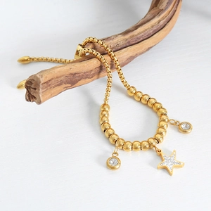 Elegant gold beaded starfish pendant bracelet with crystals on a natural wood branch