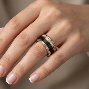 Close-up of a rose gold titanium ring featuring black carbon fiber inlay and paved zircons