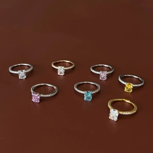 Close-up of square-cut colorful gemstones on diamond-encrusted silver and gold bands