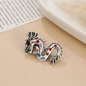 Detailed close-up of silver dragon brooch inlaid with colorful round rhinestones