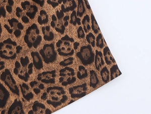 Detailed macro view of leopard print faux suede fabric texture and reinforced edge stitching