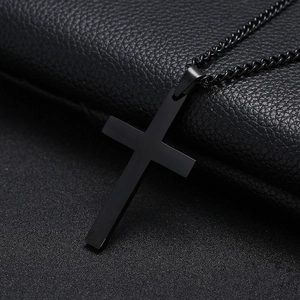 Collar minimalista con colgante de cruz de metal negro y cadena fina en fondo oscuro