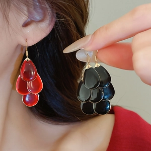 Detail of layered waterdrop tassel earrings with red and black enamel in gold plating