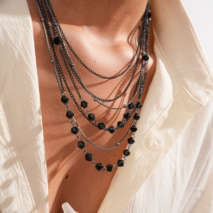 Close-up of layered necklace with black faceted beads and mixed metal chains on model
