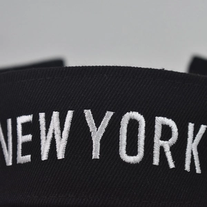 Close-up of fine white NEW YORK embroidery on black twill fabric sun hat