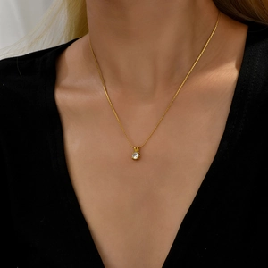 Elegant gold titanium necklace with a round cubic zirconia pendant on a model