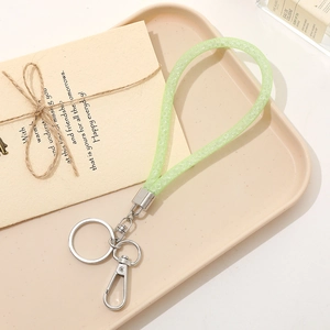 Close-up of light green glitter strap keychain with silver spring clasp on a tray