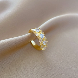Macro detail of adjustable gold plated ring with square zircon stones on silk fabric