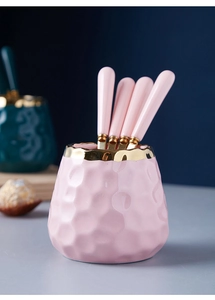 Detail of pink ceramic storage jar with gold rim and spoons with matching handles