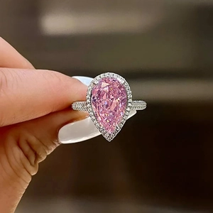 Macro view of pear-cut pink zircon ring with shimmering pavé diamonds on a silver band