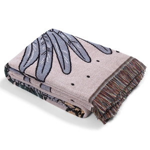 Close-up of bohemian woven blanket with leaf pattern and colorful tassel edge details
