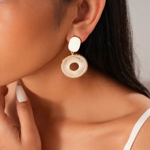 Gros plan d'un mannequin portant des boucles d'oreilles rondes dorées tressées