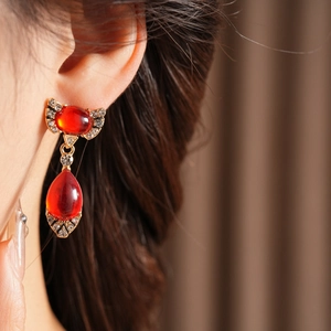 Macro detail of vintage gold bow earrings with red teardrop gems and clear rhinestones