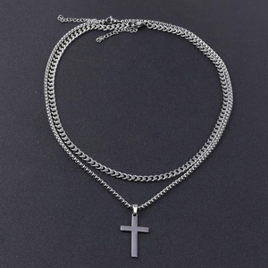 Detail of silver double-layered necklace with cross pendant and snake chain on black background