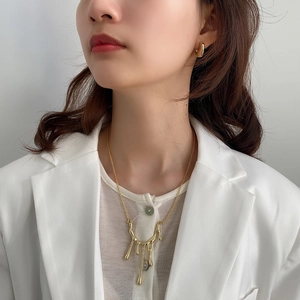 Modella che indossa collana fluida dorata e orecchini a perno in metallo minimalisti