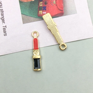 Macro detail of red enamel lipstick charms with golden textured back and top rings